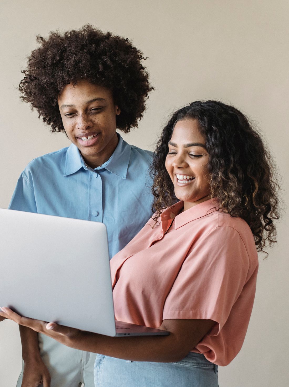 A young couple smiling as they look at their finances together on screen